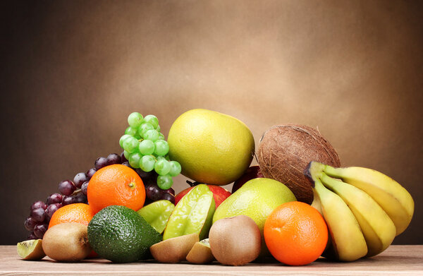 Ассортимент экзотических фруктов на деревянном столе на коричневом фоне
