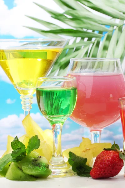 stock image Glasses of cocktails on table on blue sky background