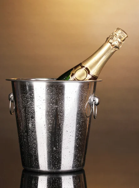 Flasche Champagner im Eimer auf braunem Hintergrund — Stockfoto