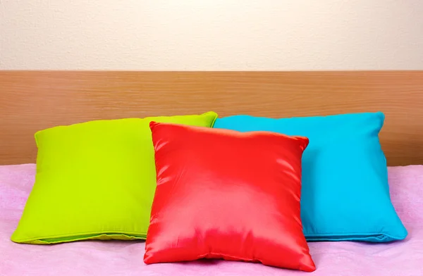Almohadas brillantes en la cama sobre fondo beige —  Fotos de Stock