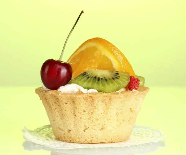 Сладкий торт с фруктами на зеленом фоне — стоковое фото