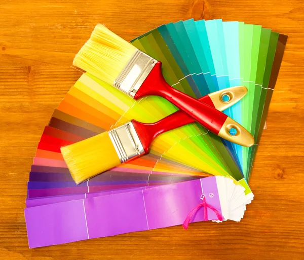 Paint brushes and bright palette of colors on wooden background — Stock Photo, Image