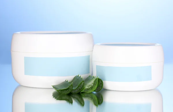 Vasi di crema con aloe vera su sfondo blu — Foto Stock