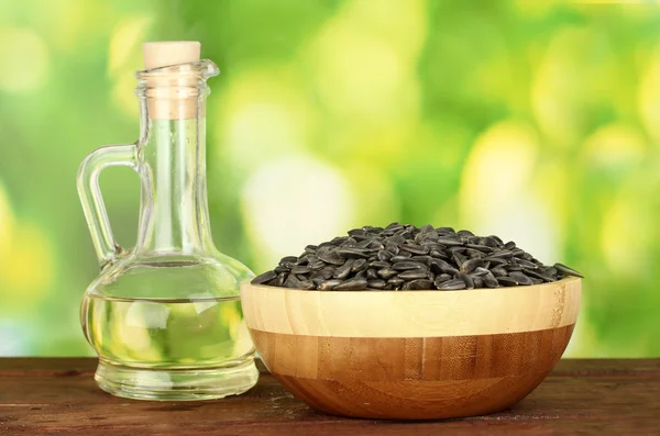Sunflower oil in small decanter with sunflower seeds on green background close-up — Stock Photo, Image