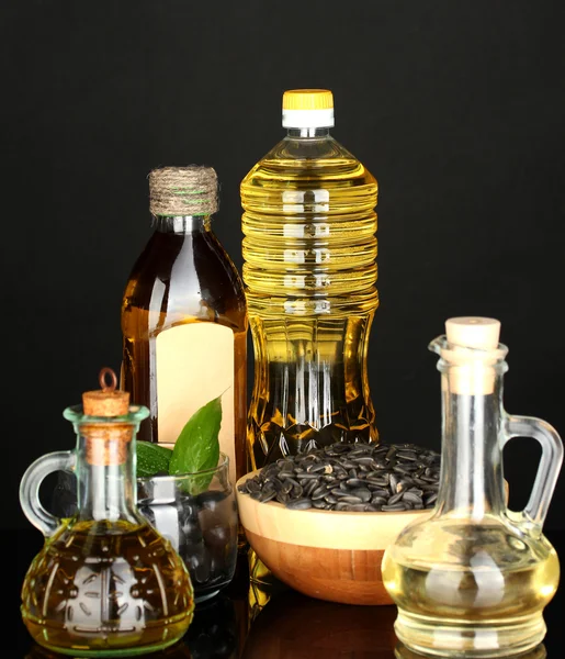Olijf- en zonnebloem olie in de flessen en kleine bezinktanks geïsoleerd op zwarte achtergrond close-up — Stockfoto
