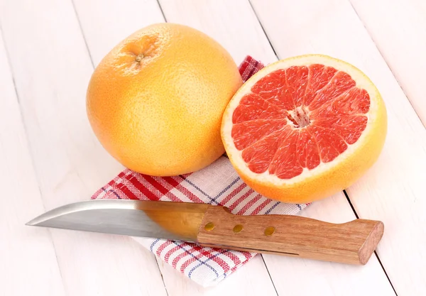 Спелый грейпфрут и половина на салфетке на деревянном фоне — стоковое фото
