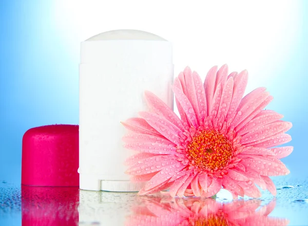 Deodorant met bloem op blauwe achtergrond — Stockfoto