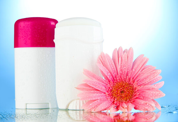 Deodorant botttles with flower on blue background