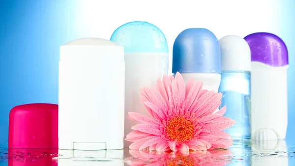 Botttles dezodorant z kwiatów na niebieskim tle — Zdjęcie stockowe