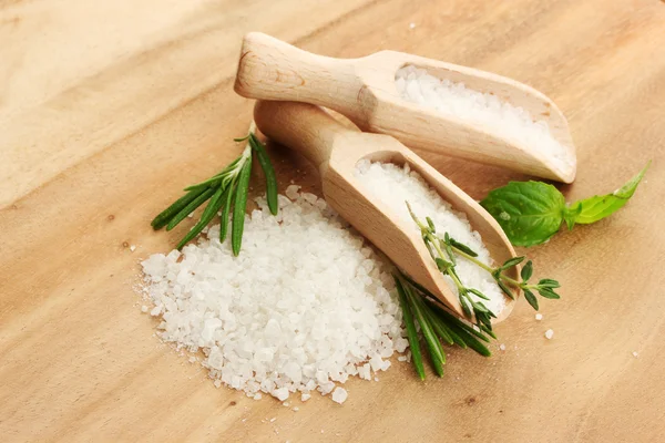 Соль в лопатах со свежим базиликом, розмарином и тимьяном на деревянном фоне — стоковое фото
