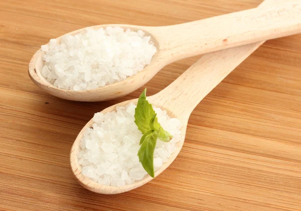 Salz in Löffeln mit frischem Rosmarin und Basilikum auf Holzgrund — Stockfoto