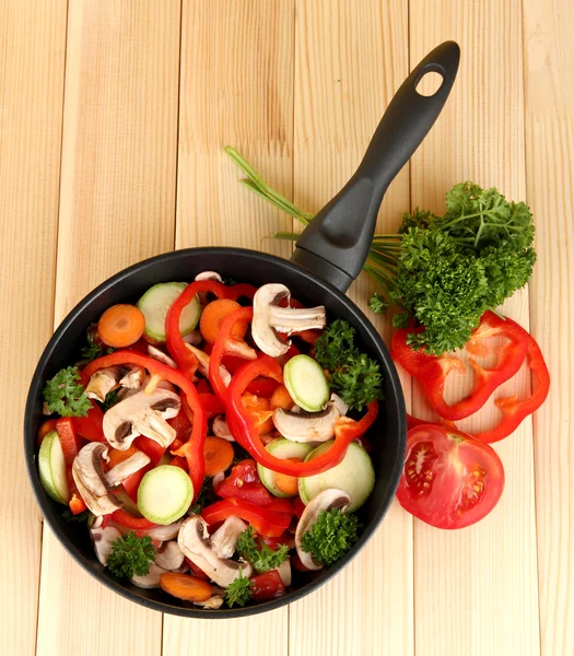 Frying pan with vegetables on wooden background — Stock Photo, Image