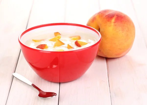 Йогурт з персиком в мисці на дерев'яному фоні — стокове фото