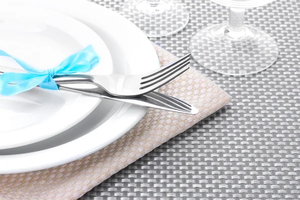 Beyaz boş tabak, çatal ve bıçak bir şerit ve gri bir masa örtüsü üzerine gözlük ile bağlı — Stok fotoğraf