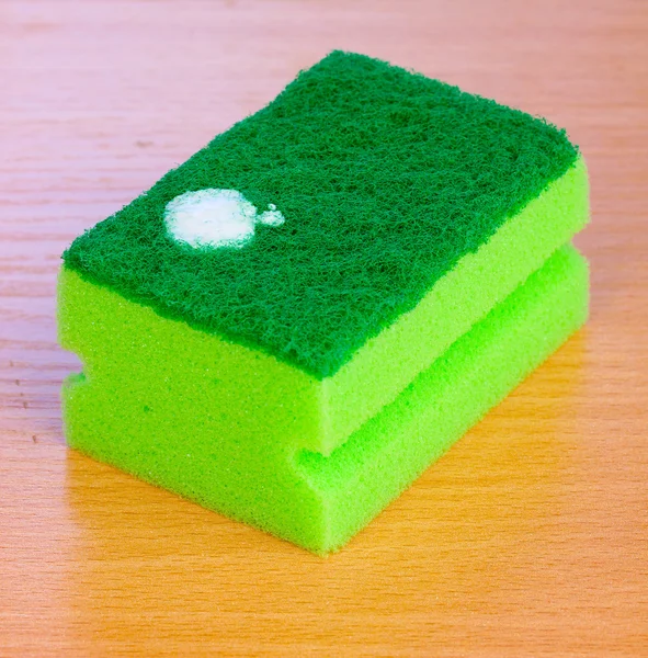 Sponge with dishwashing liquid on wooden table — Stock Photo, Image