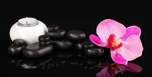 Wellness-Steine mit Orchideenblume und Kerze isoliert auf schwarz — Stockfoto