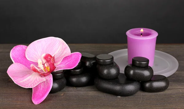 Piedras de spa con flor de orquídea y vela sobre mesa de madera sobre fondo gris — Foto de Stock