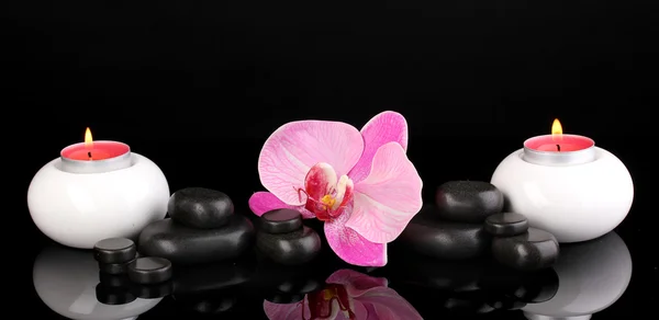 Pedras de spa com flor de orquídea e velas isoladas em preto — Fotografia de Stock