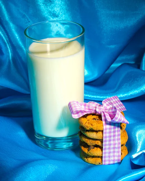 Sklenici mléka a soubory cookie na pozadí modré látky — Stock fotografie