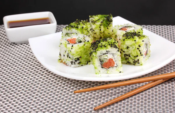Tasty rolls served on white plate with chopsticks on grey mat on grey background — Stock Photo, Image