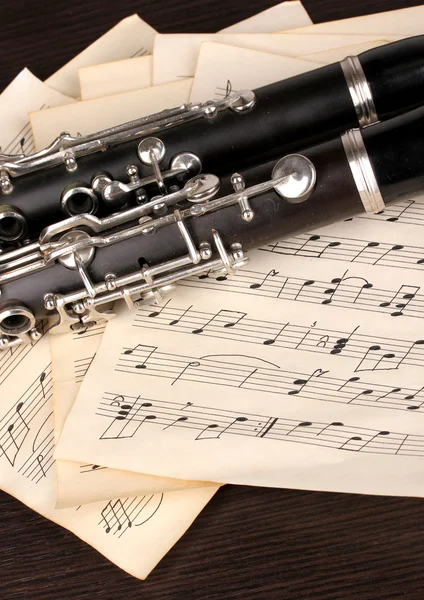 Notas musicales y clarinete sobre mesa de madera — Foto de Stock