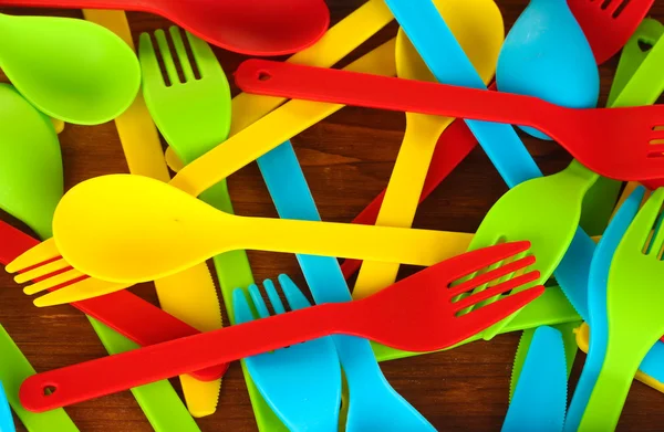 Bright plastic disposable tableware on wooden background close-up — Stock Photo, Image