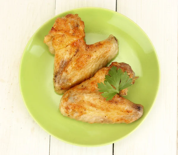 Roasted chicken wings with parsley in the plate on white wooden background close-up — Stock Photo, Image