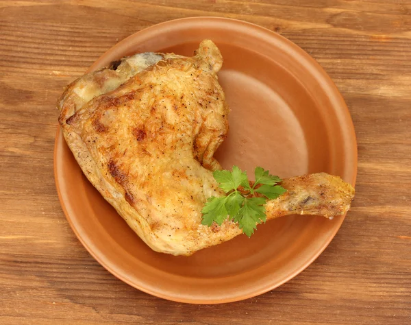 Roasted chicken leg with parsley in the plate on wooden background close-up — Stock Photo, Image
