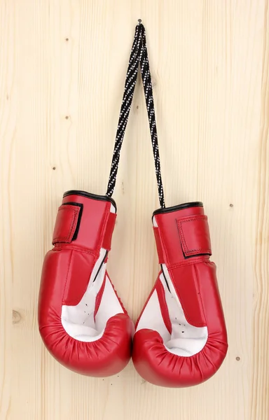 Red boxing gloves hanging on wooden background — Stock Photo, Image