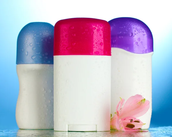 Deodorants with flower on blue background — Stock Photo, Image