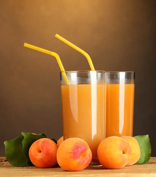Glasögon av aprikos juice på träbord på brun bakgrund — Stockfoto