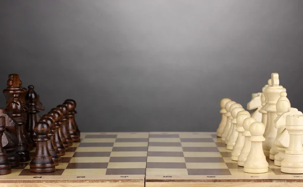Šachovnice s šachové figurky na šedém pozadí — Stock fotografie