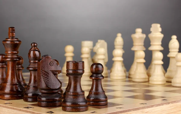 Schackbräde med schackpjäser på grå bakgrund — Stockfoto