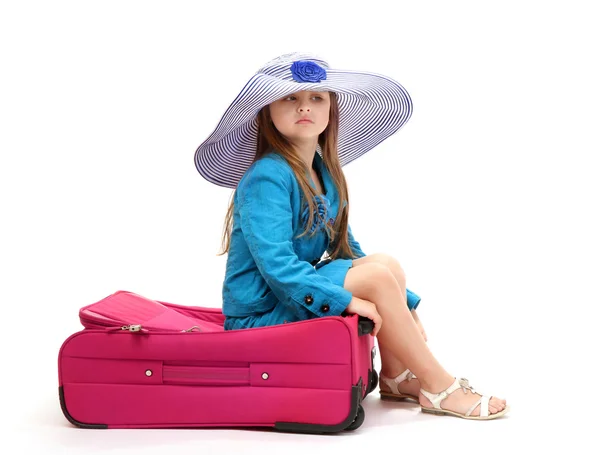 Porträt eines kleinen Mädchens auf Reisetasche mit Hut auf weißem Hintergrund — Stockfoto