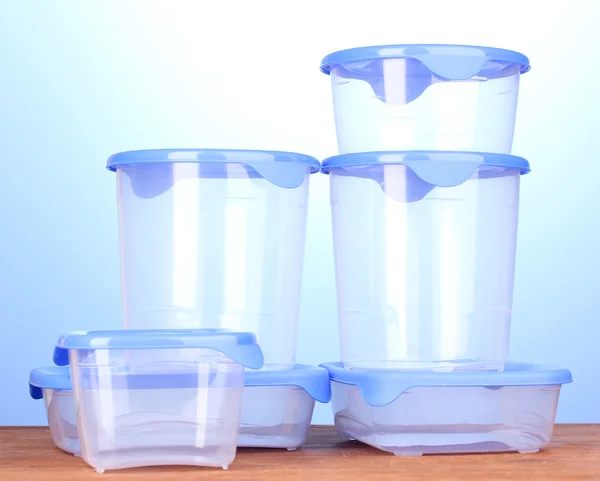 蓝色背景上的木桌子上的食物的塑料容器 — 图库照片