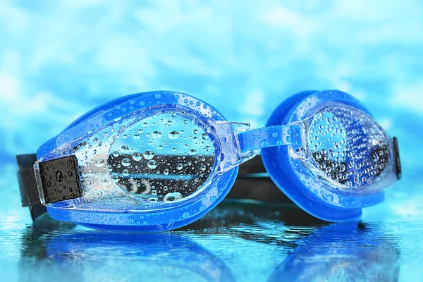 Lunettes de bain bleues avec des gouttes sur fond bleu mer — Photo
