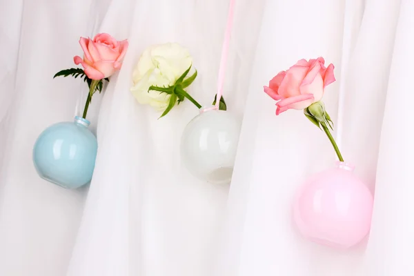 Hermosas rosas en jarrones colgando sobre fondo de tela — Foto de Stock