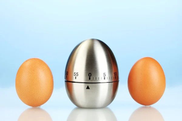 Timer uovo e uova su sfondo blu — Foto Stock