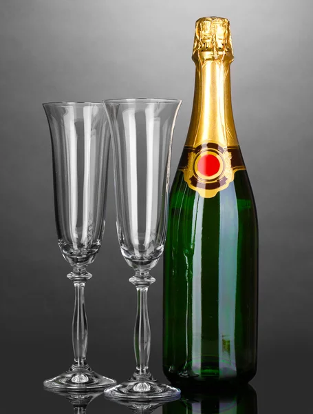 Bir şişe şampanya ve gri arka plan üzerinde kadehler — Stok fotoğraf