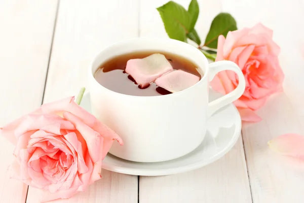 Šálek čaje s růží na bílý dřevěný stůl — Stock fotografie
