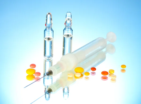 Syringe monovet, ampoules and pills on blue background — Stock Photo, Image