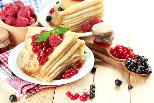Heerlijke pannenkoeken met bessen, jam en honing op houten tafel — Stockfoto
