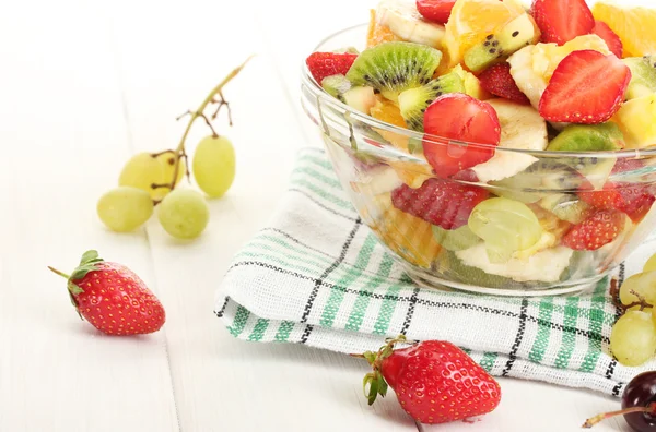Üvegtál, friss saláta gyümölcsök és bogyók a fehér fa asztal — Stock Fotó