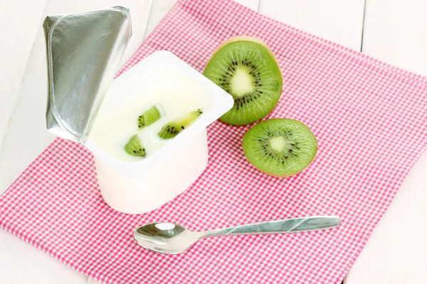 Yogurt with kiwi on napkin on wooden background — Stock Photo, Image