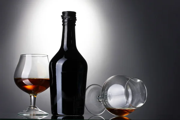 Bicchieri di brandy e bottiglia su sfondo grigio — Foto Stock