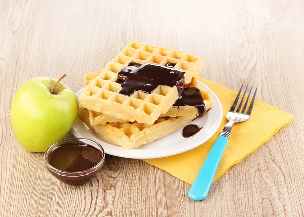 Tasty waffles with chocolate on plate on wooden background — Stock Photo, Image