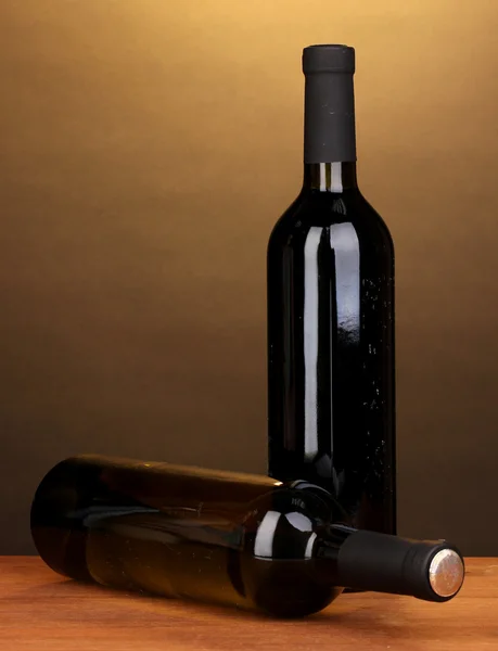Flaschen großen Weins auf Holztisch auf braunem Hintergrund — Stockfoto