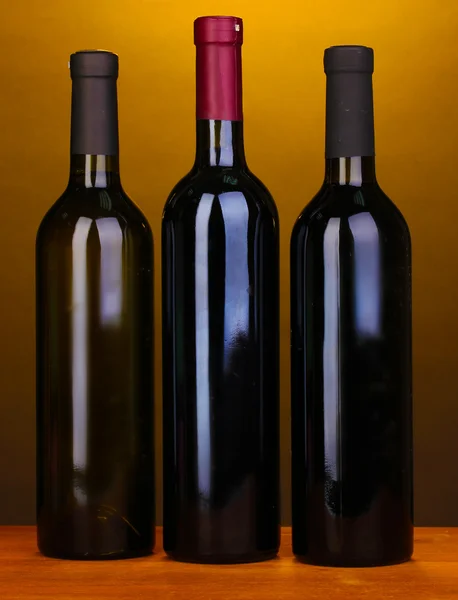 Kahverengi zemin üzerine ahşap masa üzerinde büyük şarap şişeleri — Stok fotoğraf