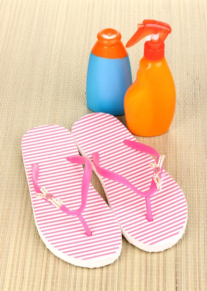Pink beach slippers and sunscreen on mat — Stock Photo, Image
