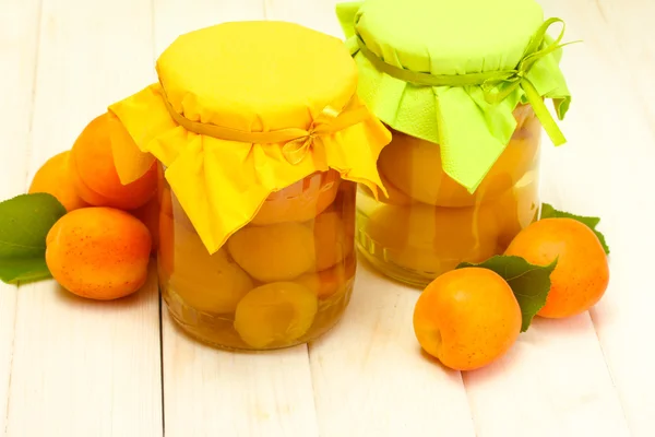 在罐子罐头的杏子和白色的木桌上成熟杏子 — 图库照片